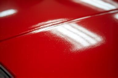 Closeup of paint correction on a glossy red car